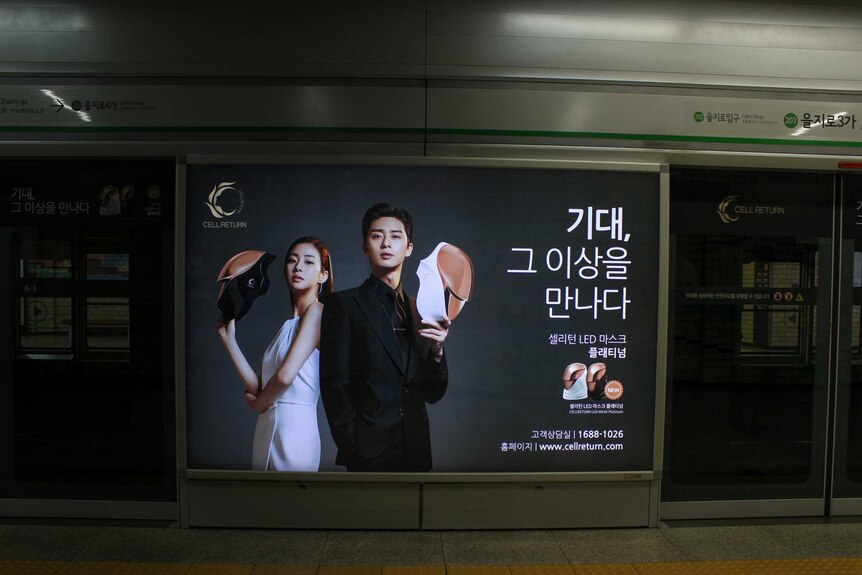 A Korean beauty advertisement of a man and a woman holdings masks.