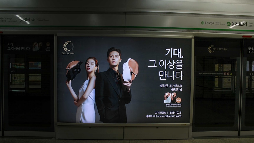 A Korean beauty advertisement of a man and a woman holdings masks.