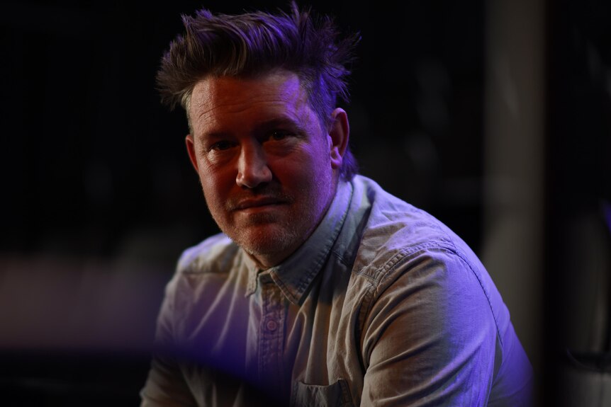 A moody dark portrait of actor and musician Eddie Perfect
