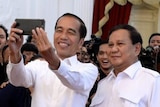 Indonesian President Jokowi and Prabowo Subianto take a selfie in front of a crowd of young people.