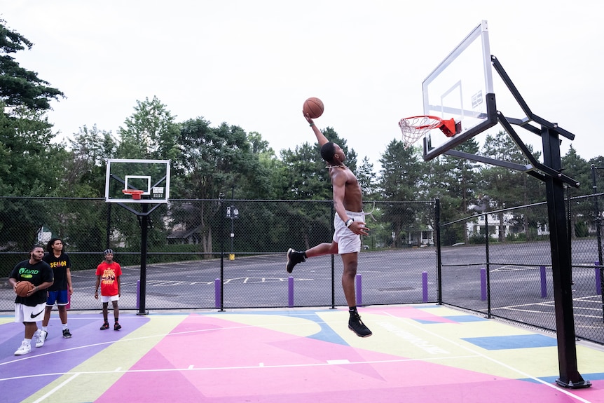 A man flies through the air for a slam dunk.