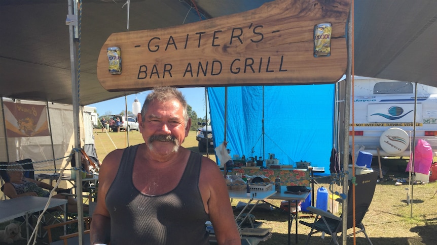man standing smiling at a campsite in front of a sign that says Gaiter's Bar and Grill