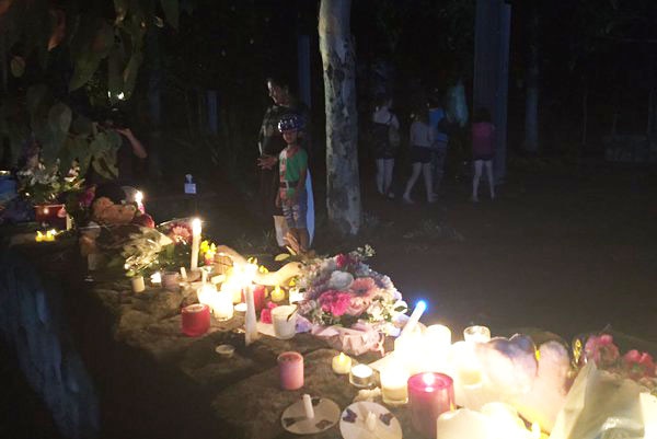 Candles, flowers and messages of support left at a vigil for Queenie Xu.