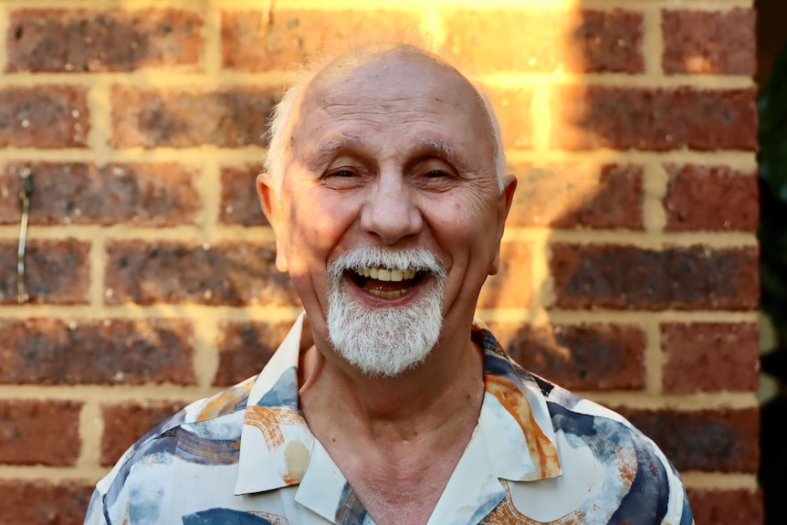 A 60-year-old man with a white beard smiling.