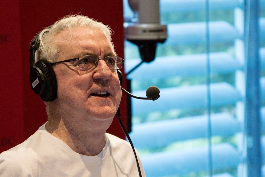 Eoin Cameron speaks into a microphone in the 720 ABC perth studios wearing a pair of headphones.