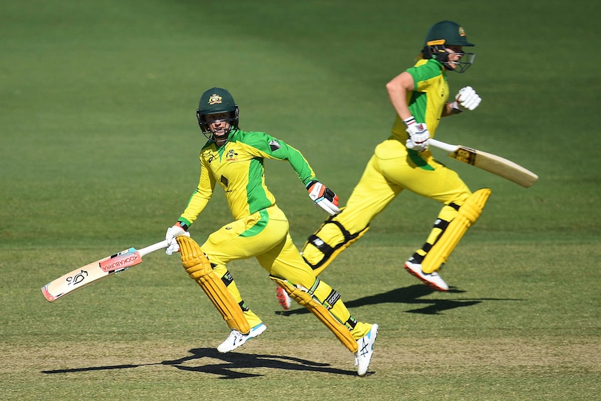 Two batters pass each other sprinting down the pitch to take a run in a women's cricket ODI.