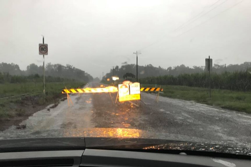 A road surrounded by two farming fields is closed at Halifax, West of Ingham, after heavy rains overnight