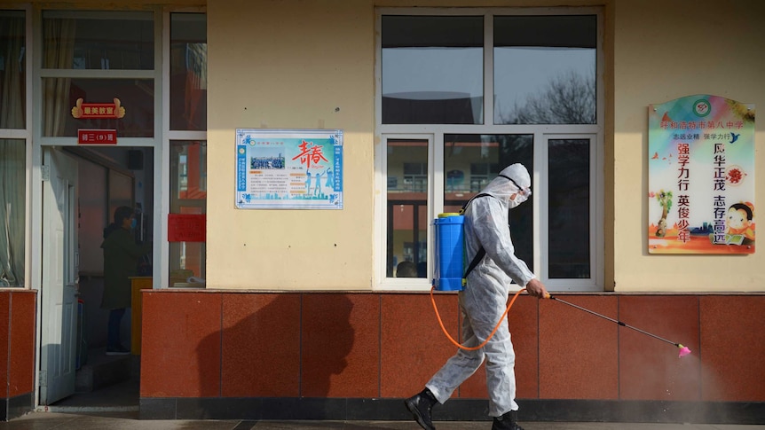A worker in a protective suit sprays disinfectant at a school in Hohhot, Inner Mongolia, China.