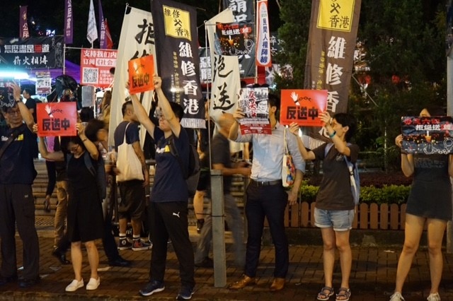 Protesters hold signs saying "No extradition to mainland China".