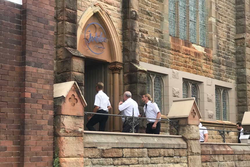 Three men entering a church.