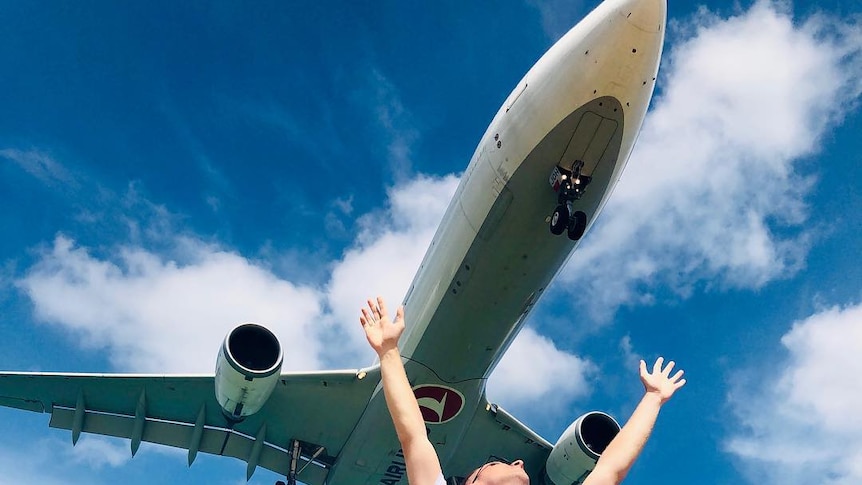 Man raises his hands as plane flies close over him