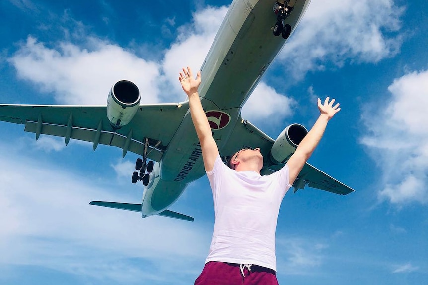 Man raises his hands as plane flies close over him