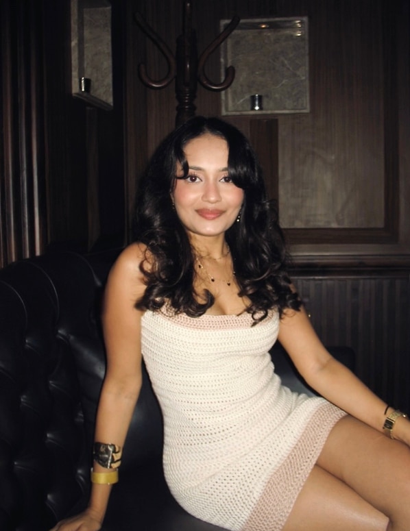 Ashna Sharma lleva un vestido blanco y está sentada.