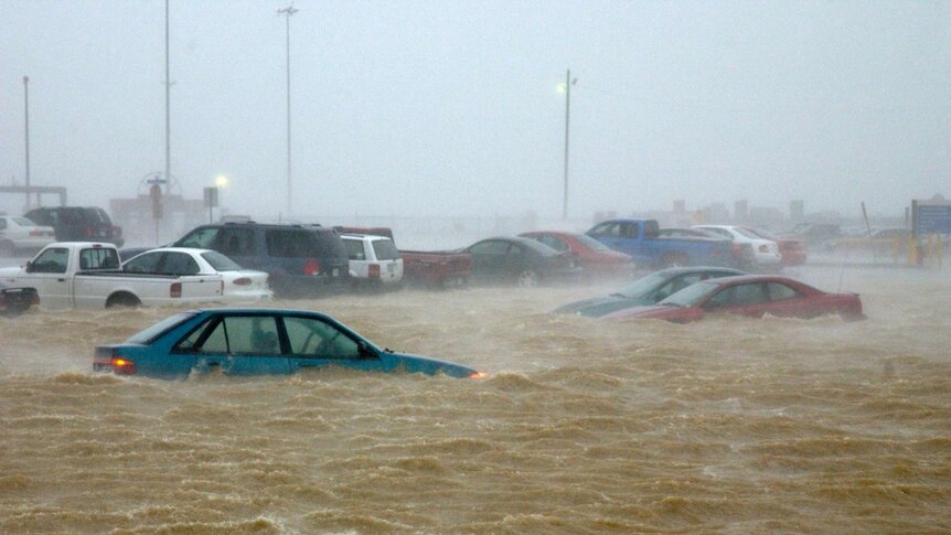 A torrent of water has submerged cars in a carpark.