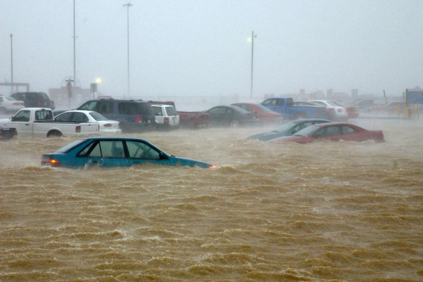 A torrent of water has submerged cars in a carpark.
