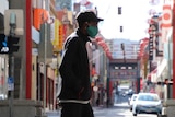 A man walking with a mask in Melbourne in early September 2020 with Chinatown in the background.