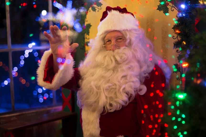 A man in a Santa costume, waving.