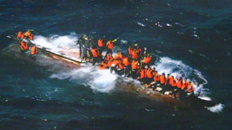 Asylum seekers cling to their upturned vessel.