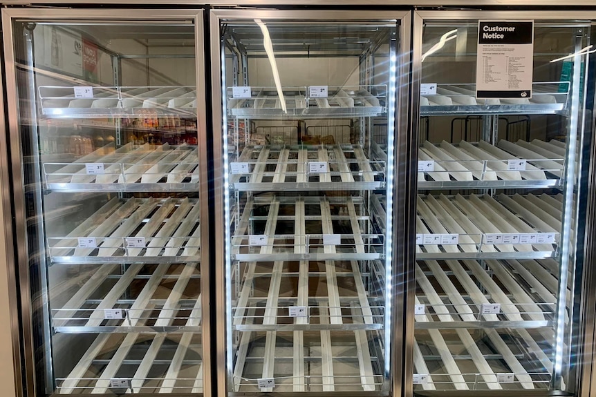 Empty refrigerated milk shelves in a shop