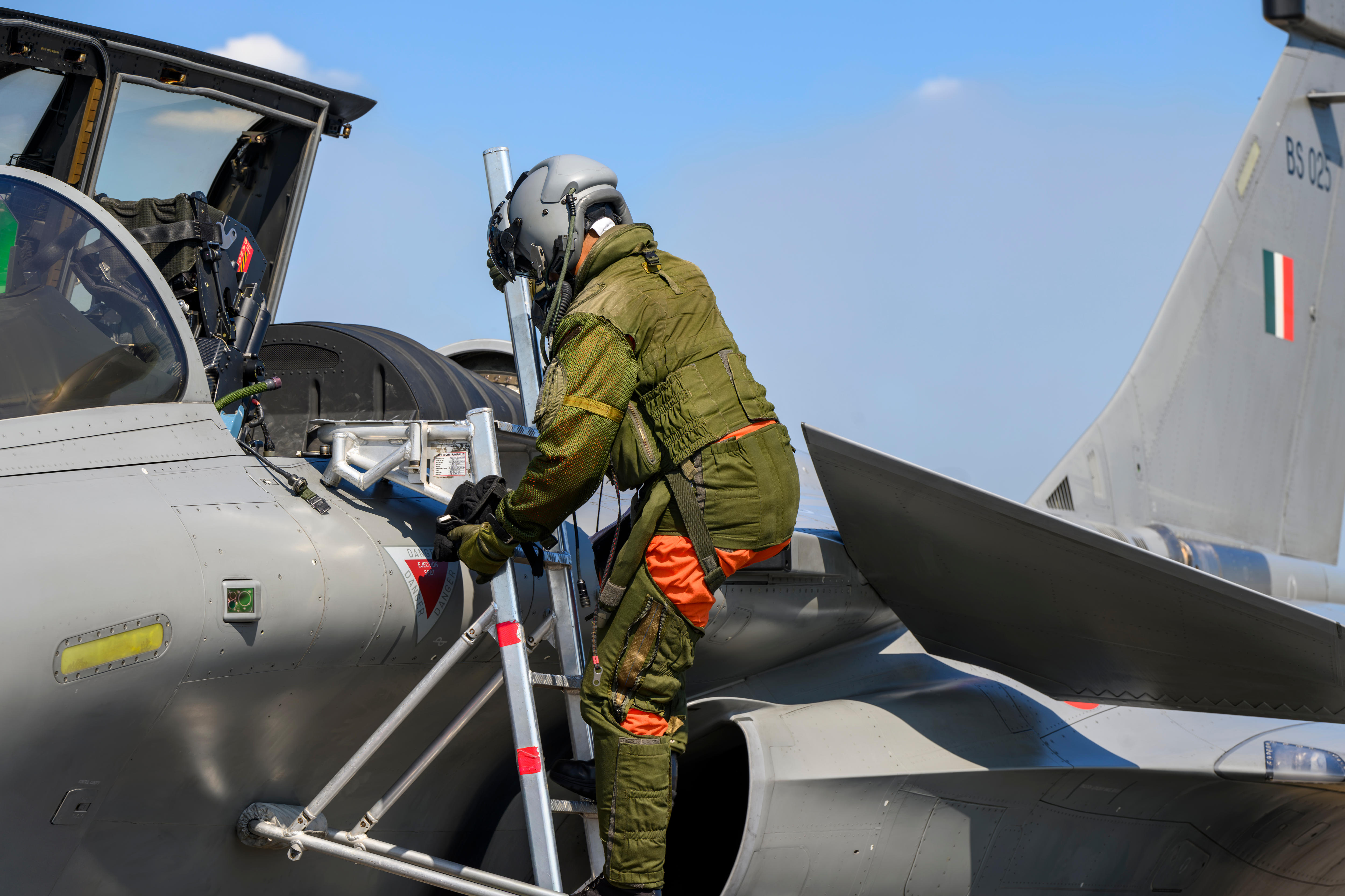 A man climbs down a ladder out of a fighter jet's cockpit.