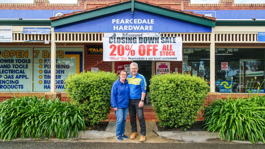 A couple pose for a photo in front of a hardware store