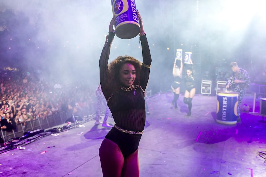 One of Client Liaison's dancers holding aloft an oversized can of Fosters at their Splendour 2017 set.