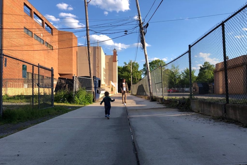 Man kicking soccer ball to small boy in deserted street.