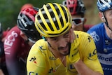 Julian Alaphilippe surrounded by competitors wipes his face during a gruelling mountain climb at the Tour de France