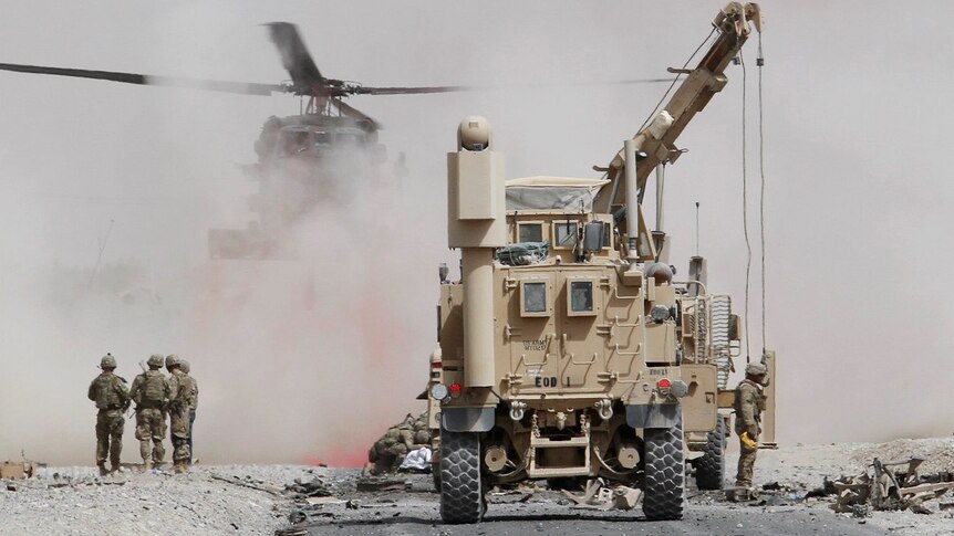 US troops assess the damage to an armoured vehicle of NATO-led military coalition after a suicide attack in Kandahar.