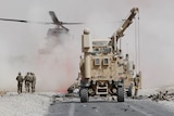 US troops assess the damage to an armoured vehicle of NATO-led military coalition after a suicide attack in Kandahar.