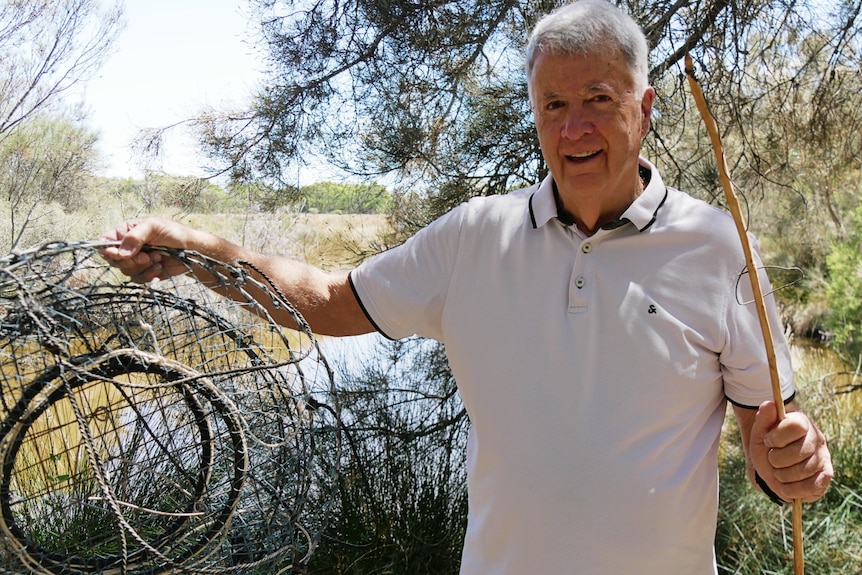 A man stands with some marron fishing equipment.