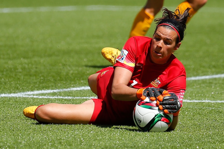 Lydia Williams makes a save wearing a red football kit.