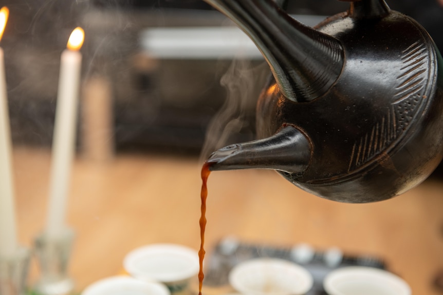A pot of steaming coffee being poured.
