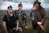 Chris Coupland, Warren Darragh and Bill Flowers pose for a photo on a cliff.