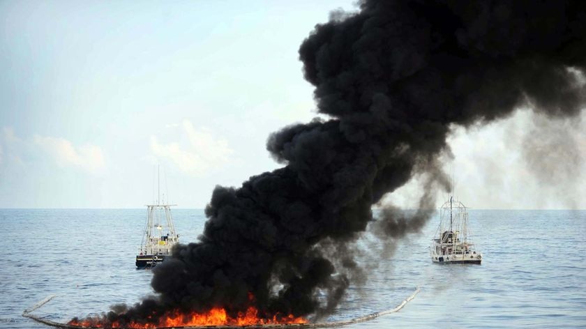 Fishing vessels pull an oil boom during a controlled oil fire off the Louisiana coast