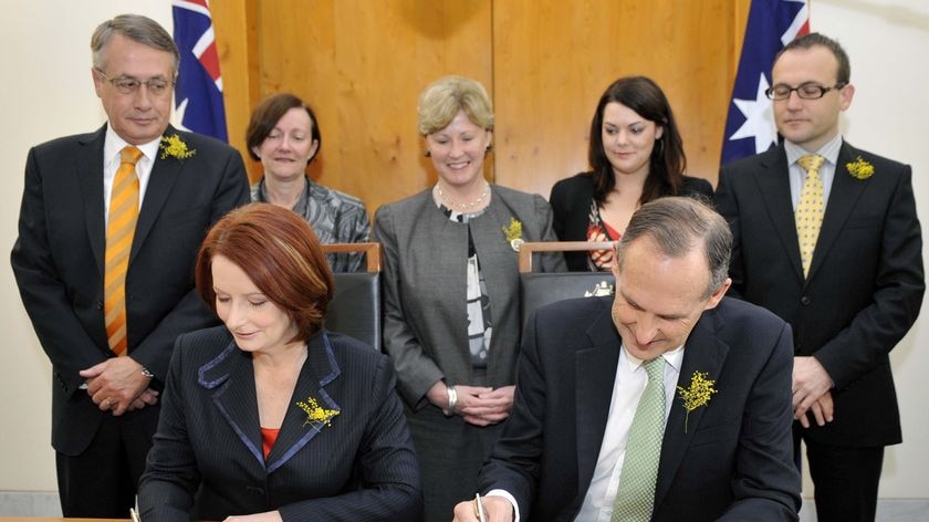 Julia Gillard and Bob Brown sign on the line (AAP: Alan Porritt)