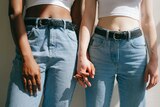 Two women holding hands, close up of their mid section and jeans in a story about the most common sex misconceptions.