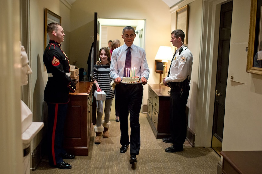 President Barack Obama carries birthday cake in the corridors of the West Wing