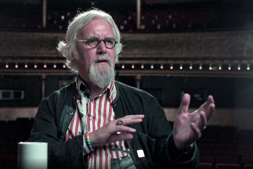 Sir Billy Connolly raises his hands as he is interviewed