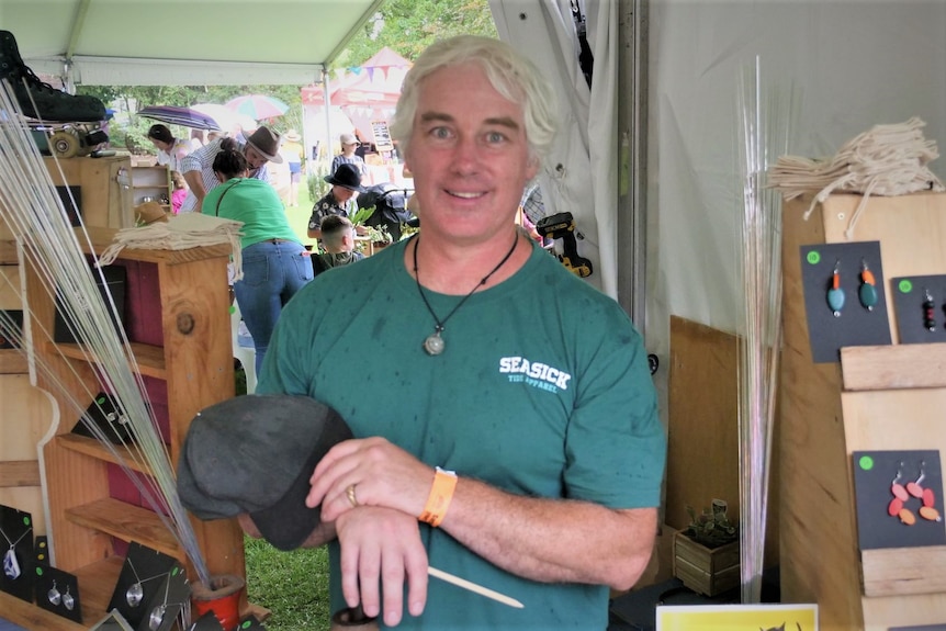 A man standing with his arms partly crossed in a vendor space at a festival 