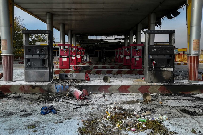Petrol pumps at a petrol station have been burned, with ash and debris on the ground