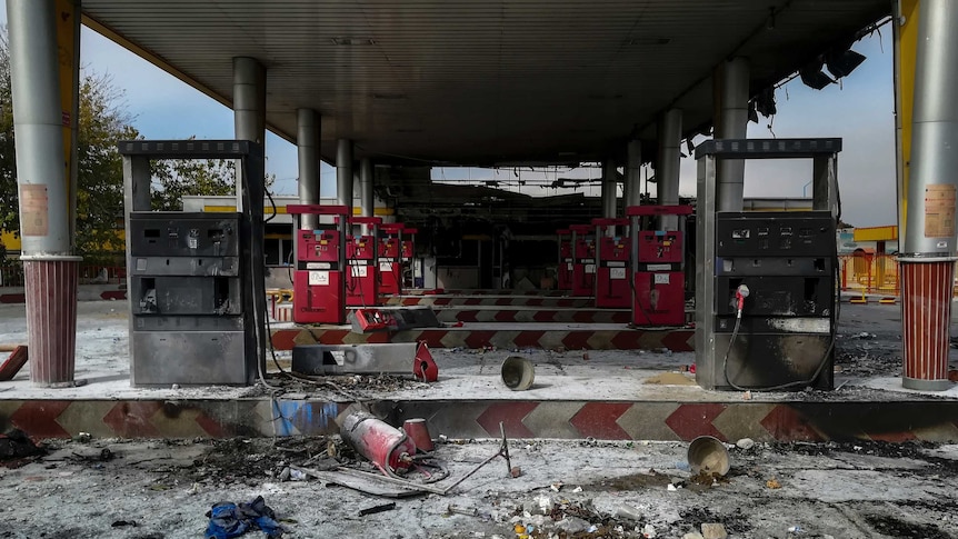 Petrol pumps at a petrol station have been burned, with ash and debris on the ground