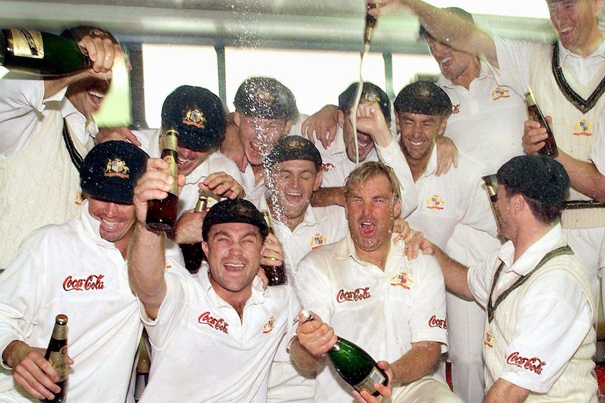 Cricket team celebrates victory inside a dressing room with alcohol.