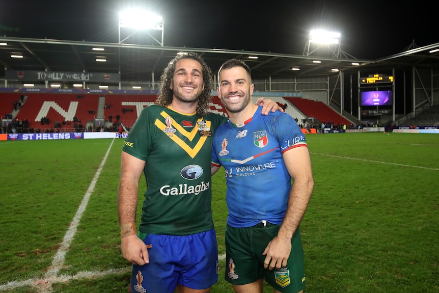 An Italian player and an Australian player pose for a picture wearing each other's jerseys after a Rugby League World Cup game.