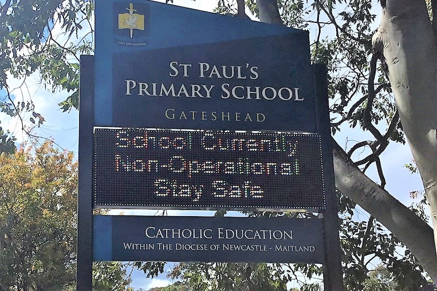 A sign outside a school reads 'School currently non-operational'.