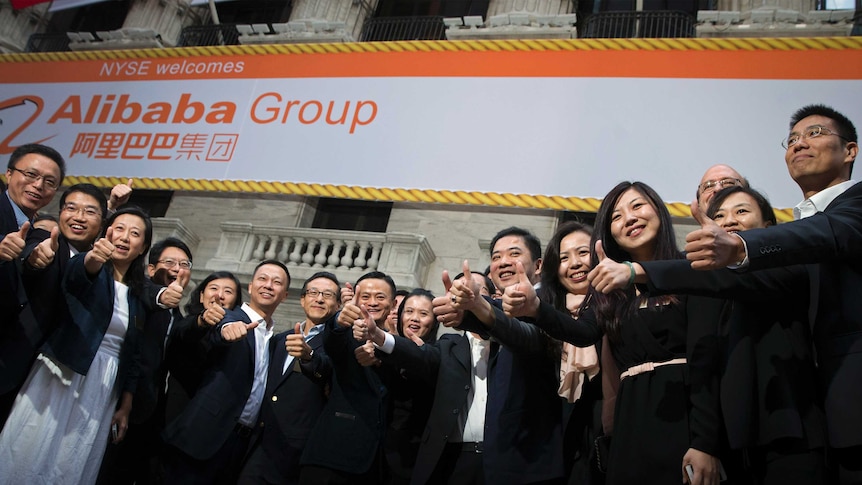 Alibaba Group Holding Ltd founder Jack Ma (C) and Joseph Tsai (center L), vice chairman and co-founder, pose with employees as they arrive for the company's initial public offering (IPO), at the New York Stock Exchange in New York September 19, 2014.