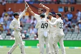 Mitchell Starc holds his hands up as four people gather around him