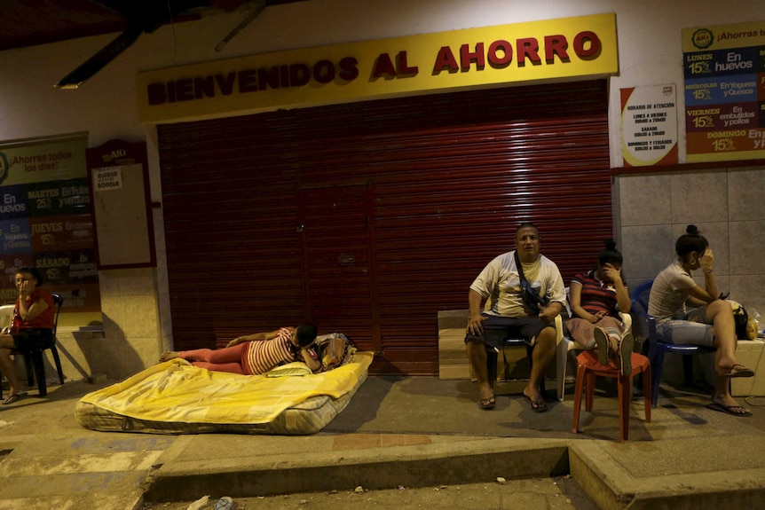 One woman sleeps on a mattress, others rest on pavement.