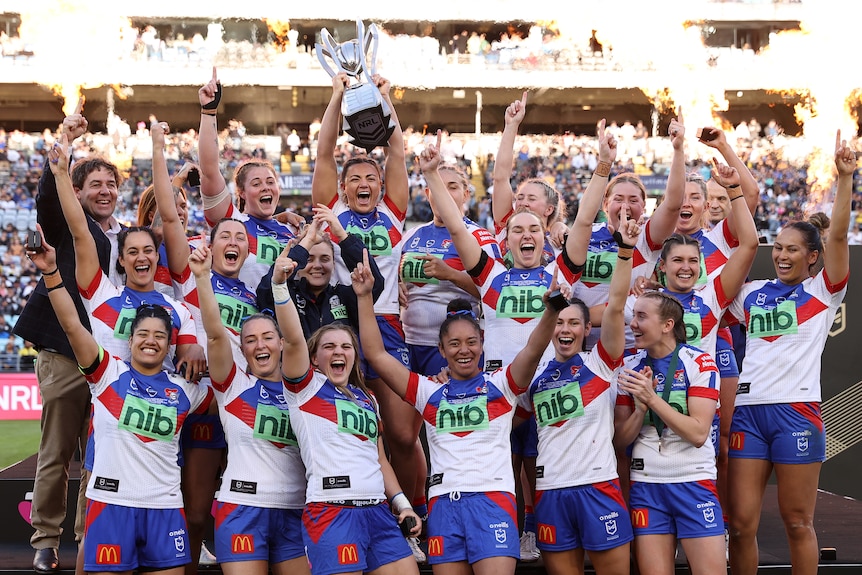 Newcastle Knights NRLW players celebrate with the premiership trophy.