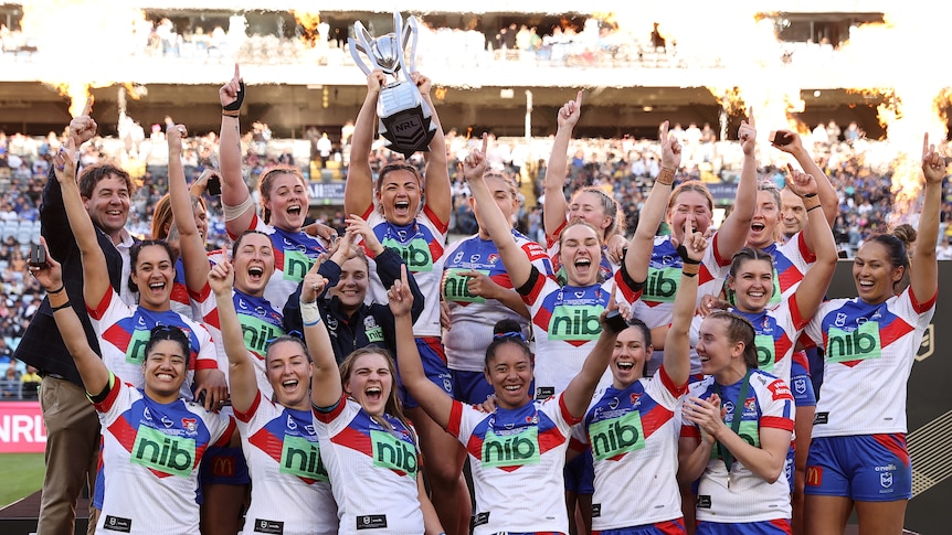 Newcastle Knights NRLW players celebrate with the premiership trophy.